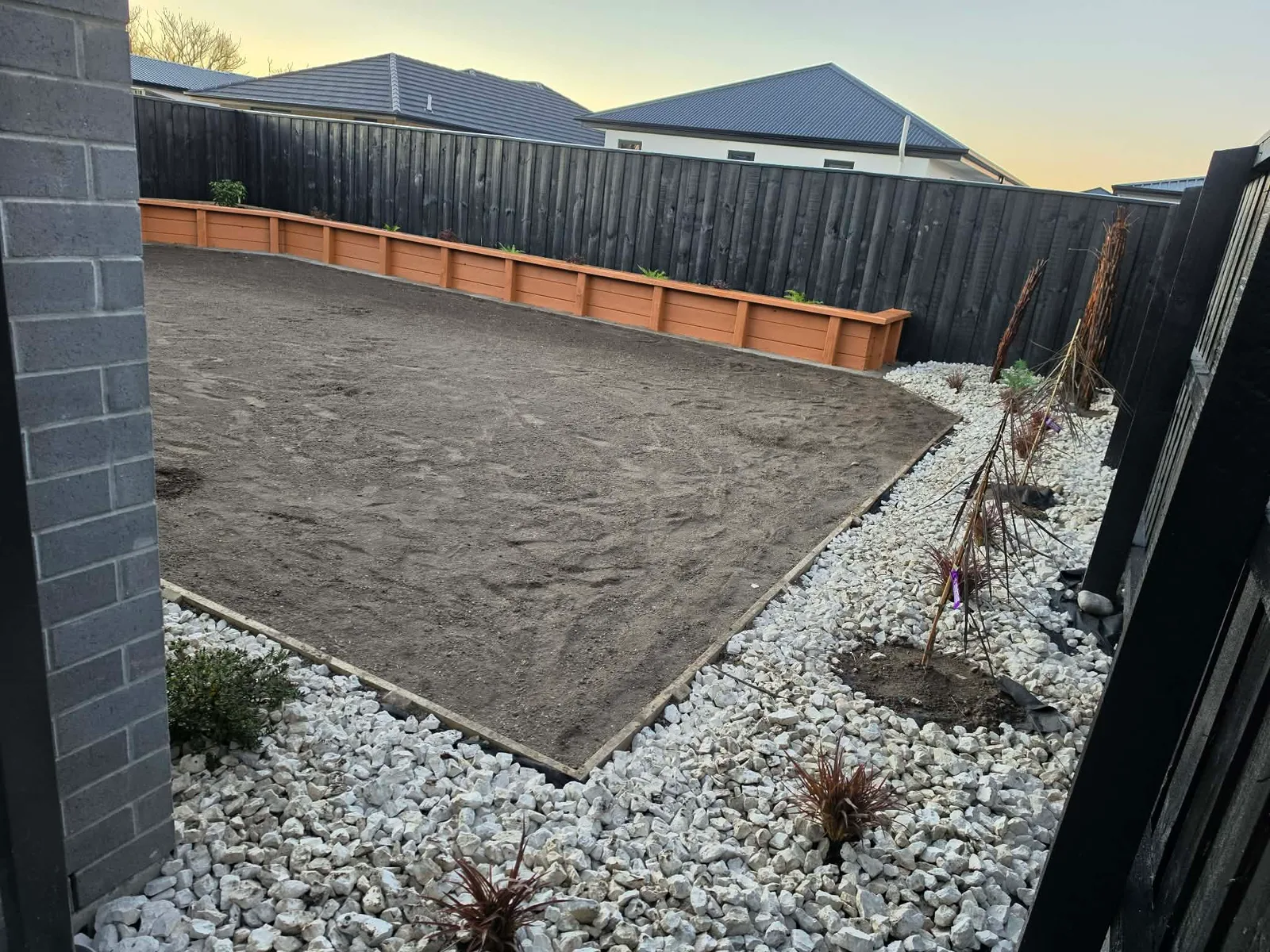 Rear yard showing white gravel borders, timber planter beds and prepared lawn area at 25 Derbridge Street