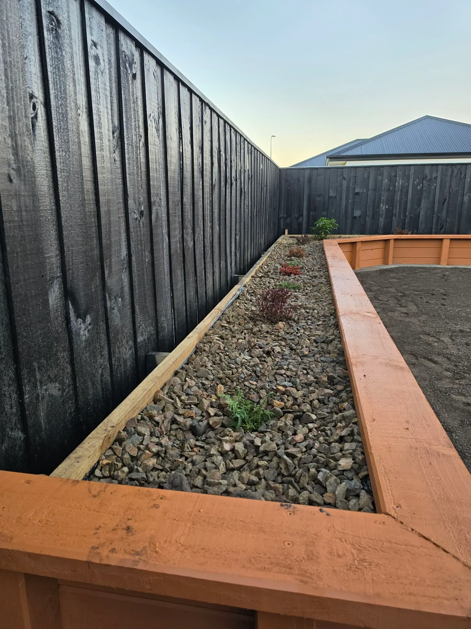 Side yard access with gravel pathway and black timber screening at 25 Derbridge Street